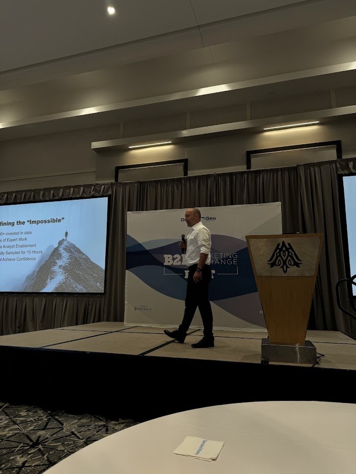 An Elynox keynote in progress — a speaker presenting the AI-native growth approach to a seated room